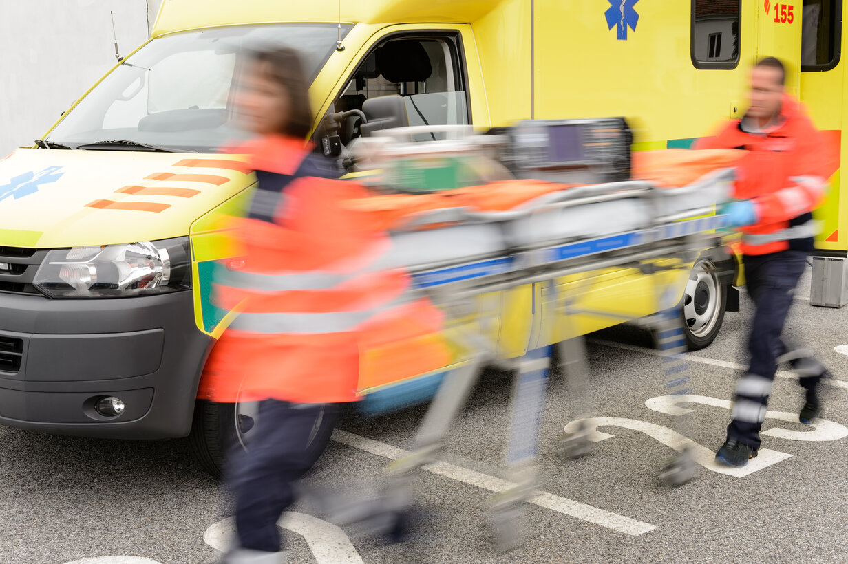 Running blurry paramedics team with stretcher and ambulance car